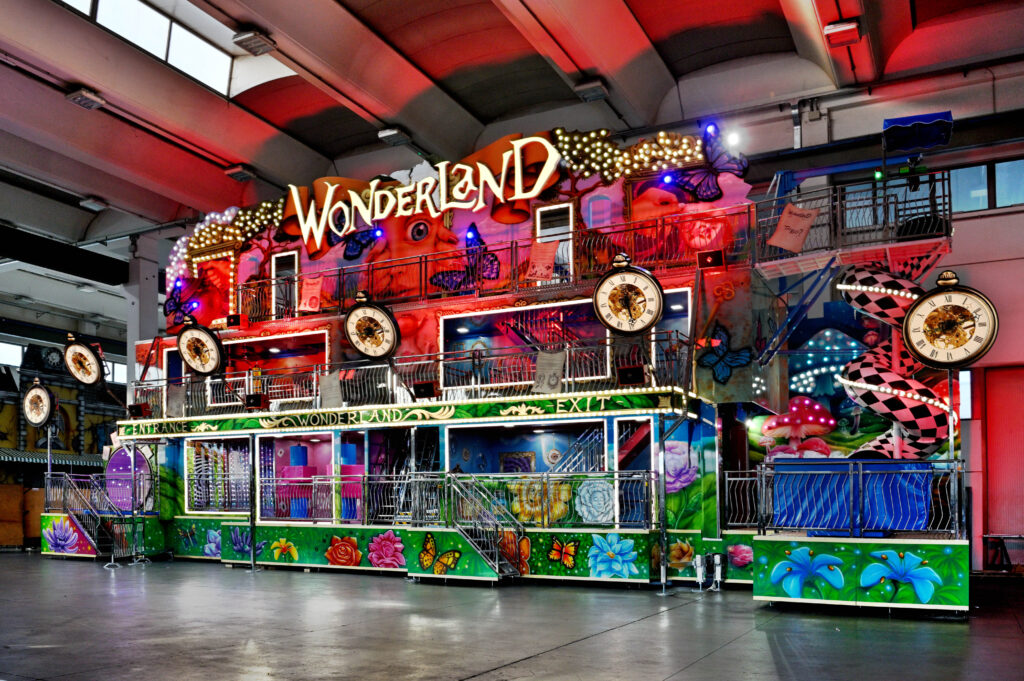 Colorful indoor carnival ride facade labeled 'Wonderland' with clocks, butterflies, and bright lights.